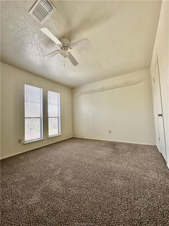 unfurnished room featuring carpet, ceiling fan, and a textured ceiling