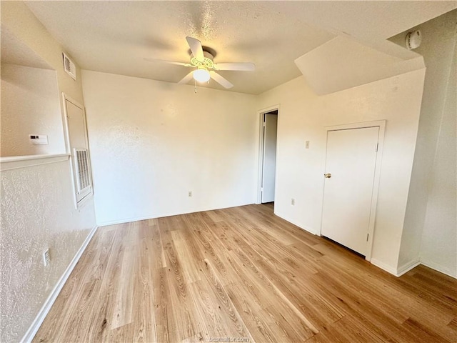 spare room with ceiling fan, light hardwood / wood-style floors, and a textured ceiling