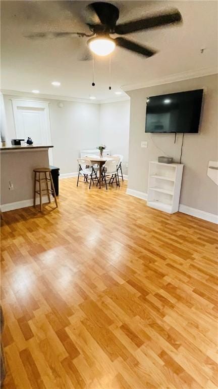 living room with baseboards, ornamental molding, ceiling fan, and wood finished floors