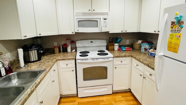 kitchen with light wood finished floors, white cabinets, a sink, light stone countertops, and white appliances