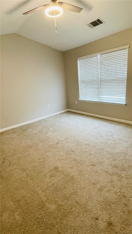 carpeted empty room featuring ceiling fan, visible vents, vaulted ceiling, and baseboards