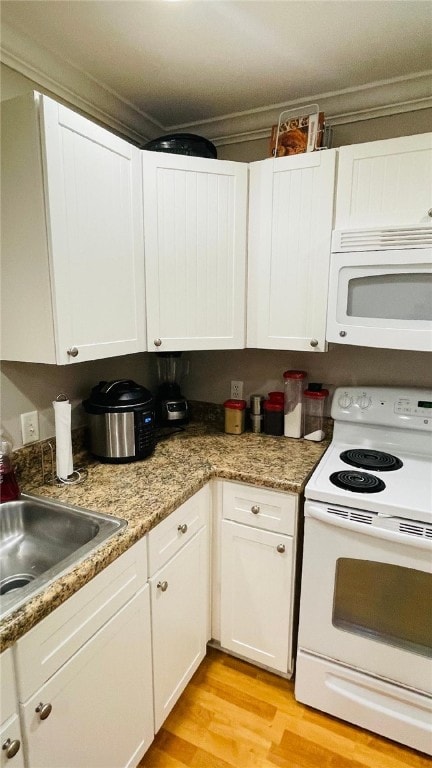 kitchen featuring white appliances, white cabinetry, light wood finished floors, and a sink