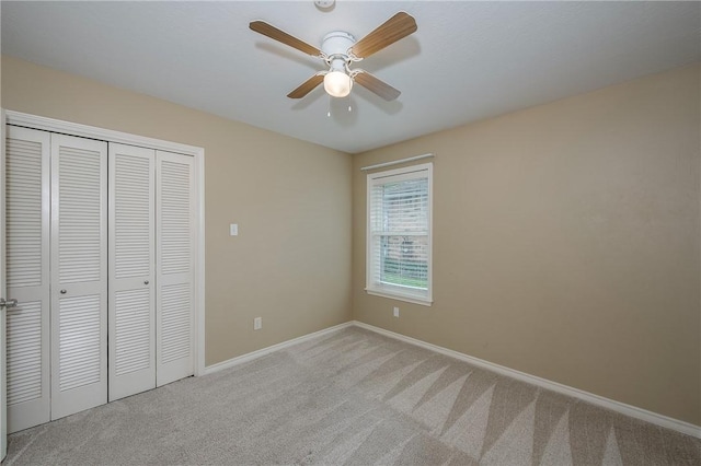 unfurnished bedroom featuring light carpet, ceiling fan, baseboards, and a closet