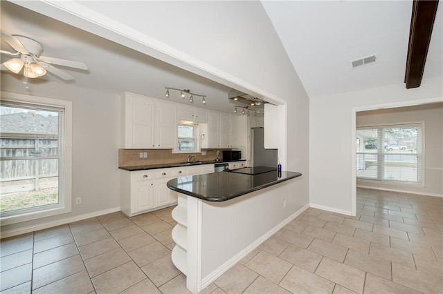 kitchen with a peninsula, a sink, visible vents, white cabinets, and dark countertops