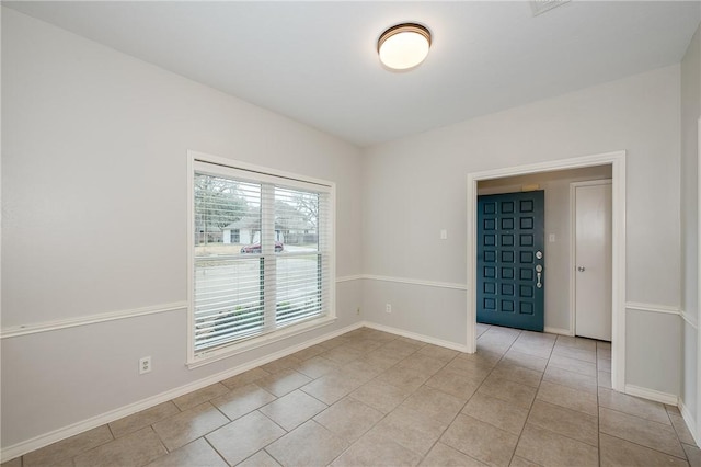 empty room with light tile patterned floors and baseboards