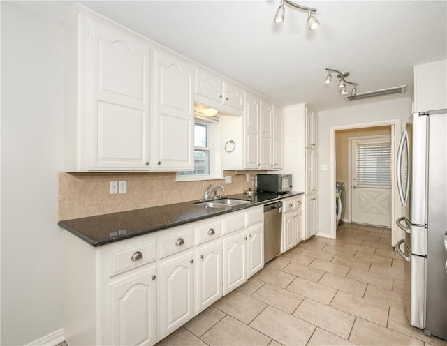 kitchen with a sink, white cabinetry, appliances with stainless steel finishes, tasteful backsplash, and dark countertops