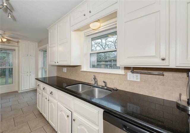 kitchen with tasteful backsplash, dark countertops, white cabinetry, and a sink