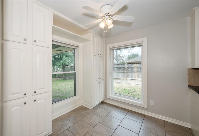 entryway with light tile patterned floors, a ceiling fan, and baseboards