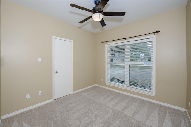 empty room featuring light colored carpet, ceiling fan, and baseboards