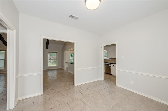 empty room featuring light tile patterned floors, visible vents, and baseboards