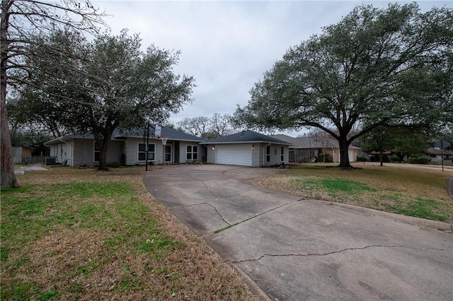 ranch-style house featuring driveway, an attached garage, and a front yard