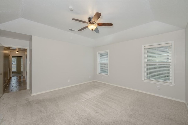 empty room featuring baseboards, a raised ceiling, a ceiling fan, and light colored carpet