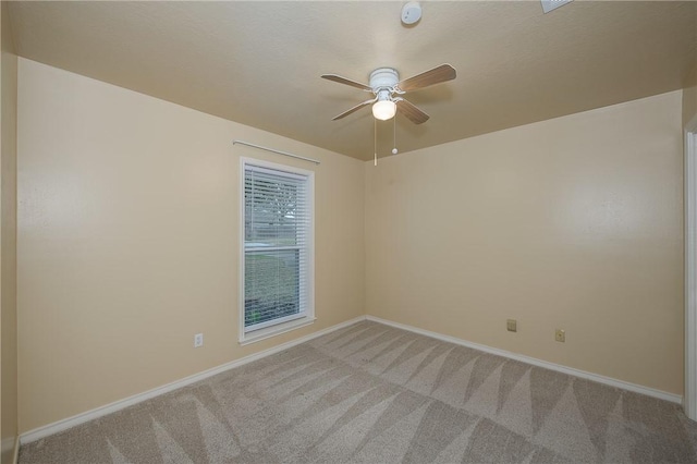 unfurnished room featuring light colored carpet, ceiling fan, and baseboards