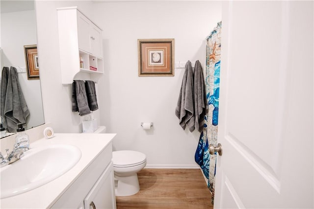 full bath with toilet, wood finished floors, vanity, and baseboards