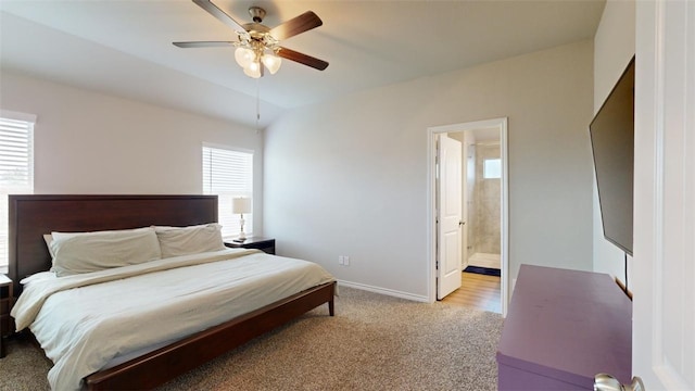 bedroom featuring vaulted ceiling, ceiling fan, connected bathroom, and light colored carpet