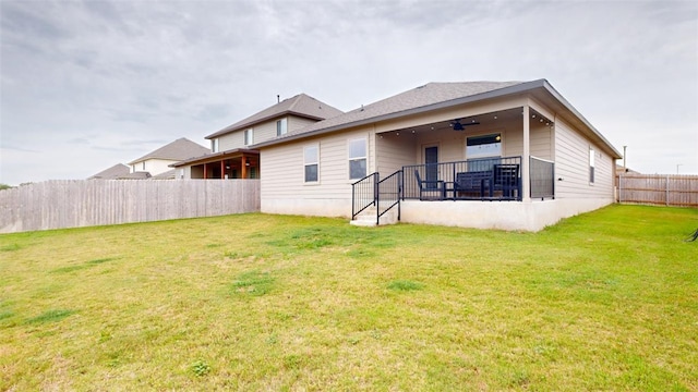 rear view of property featuring ceiling fan and a lawn