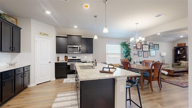 kitchen featuring sink, decorative light fixtures, a center island with sink, light hardwood / wood-style flooring, and stainless steel appliances