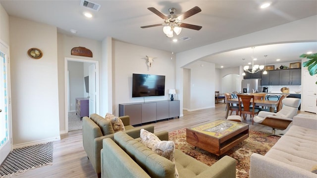 living room featuring ceiling fan with notable chandelier and light hardwood / wood-style floors