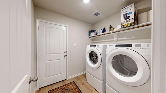 laundry area with separate washer and dryer and light hardwood / wood-style flooring