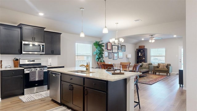 kitchen featuring a breakfast bar, sink, appliances with stainless steel finishes, an island with sink, and pendant lighting