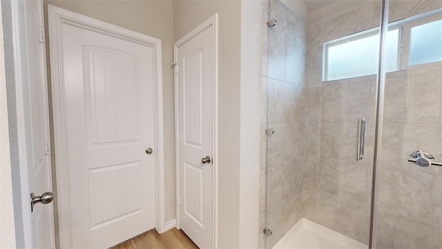 bathroom with hardwood / wood-style flooring and a shower with shower door