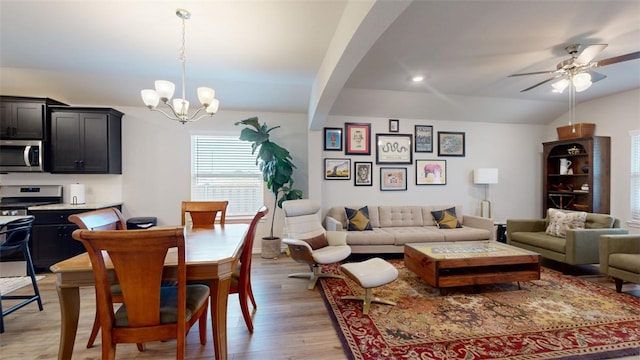 living room featuring ceiling fan with notable chandelier, light hardwood / wood-style flooring, and vaulted ceiling with beams