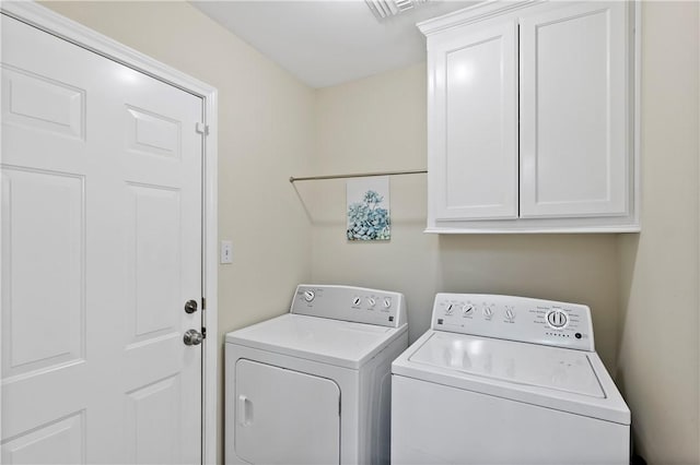 clothes washing area featuring washing machine and clothes dryer, cabinet space, and visible vents