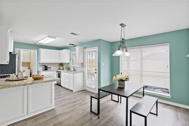 kitchen featuring pendant lighting, light stone countertops, white cabinets, and a sink