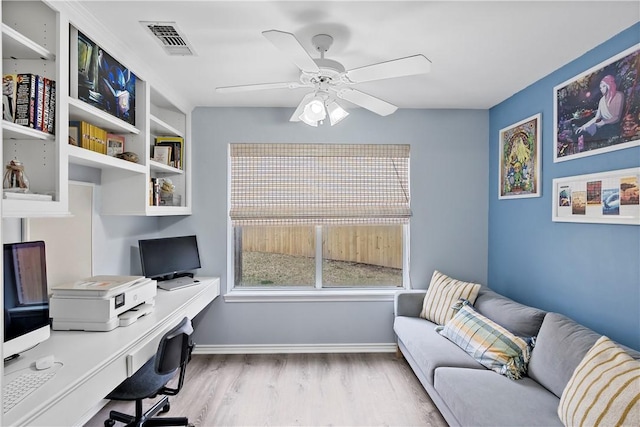 office featuring ceiling fan, visible vents, baseboards, light wood finished floors, and built in study area