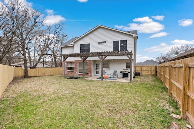 back of house with brick siding, a lawn, a patio area, and a fenced backyard