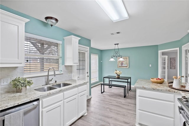 kitchen featuring tasteful backsplash, stainless steel dishwasher, hanging light fixtures, a sink, and white cabinetry