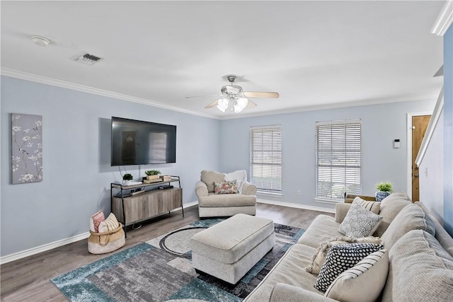 living area featuring baseboards, visible vents, wood finished floors, and ornamental molding