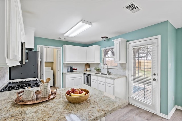 kitchen featuring a sink, visible vents, white cabinetry, light stone countertops, and washer / dryer