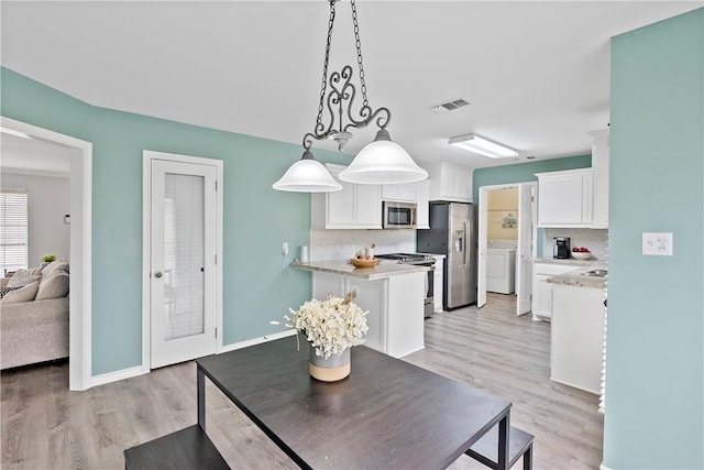 dining space with baseboards, visible vents, light wood finished floors, and washer and dryer