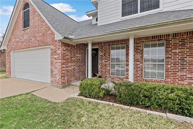 entrance to property with a garage, a porch, concrete driveway, brick siding, and a shingled roof