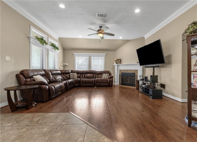 living room featuring a tiled fireplace, ceiling fan, crown molding, and lofted ceiling