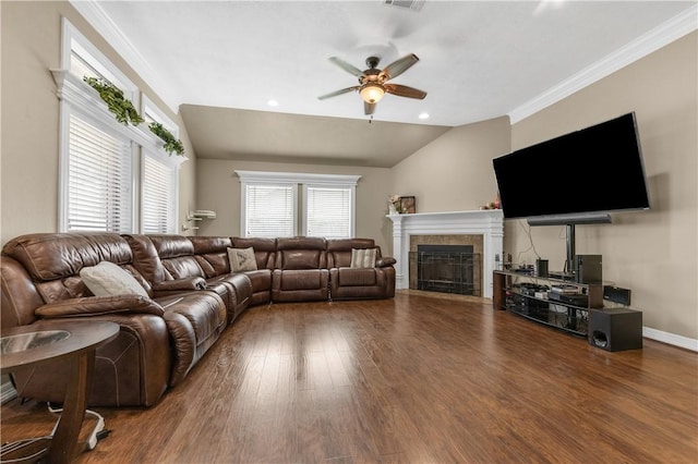 living room with dark hardwood / wood-style flooring, ornamental molding, vaulted ceiling, ceiling fan, and a tile fireplace