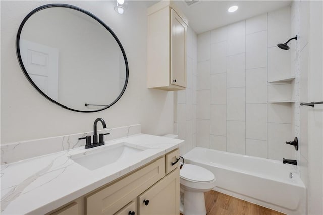 full bathroom featuring vanity, wood-type flooring, tiled shower / bath combo, and toilet