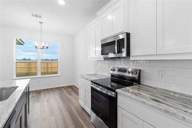 kitchen with light stone countertops, backsplash, stainless steel appliances, hardwood / wood-style flooring, and white cabinets