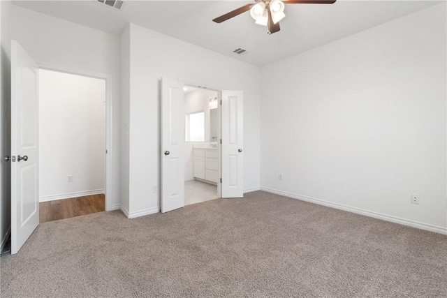 unfurnished bedroom featuring light carpet, ensuite bath, and ceiling fan