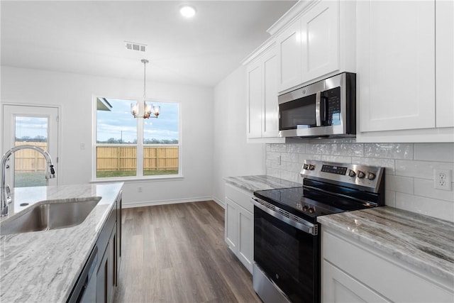 kitchen with decorative backsplash, light stone countertops, stainless steel appliances, sink, and white cabinets