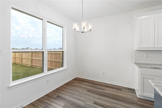 unfurnished dining area featuring dark hardwood / wood-style floors and a chandelier