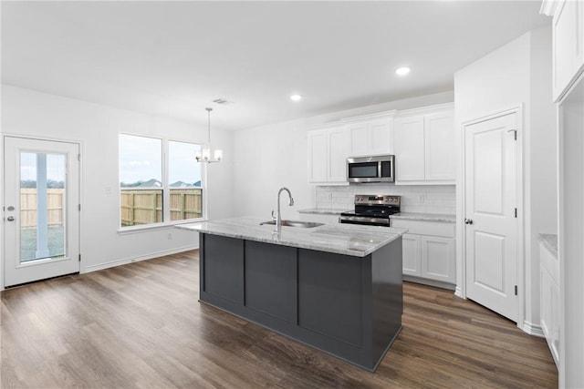 kitchen featuring sink, appliances with stainless steel finishes, decorative light fixtures, light stone counters, and white cabinetry