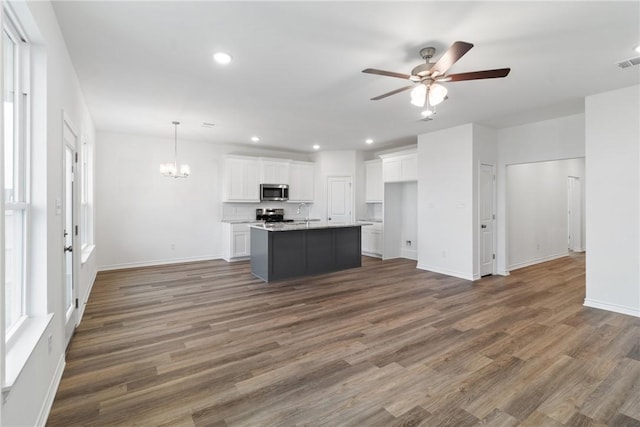 kitchen featuring stainless steel appliances, a kitchen island with sink, dark wood-type flooring, pendant lighting, and white cabinets