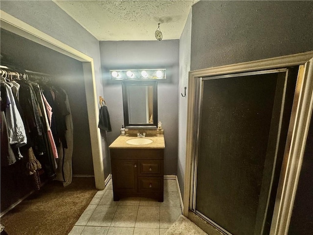 bathroom with tile patterned flooring, a textured ceiling, vanity, and an enclosed shower