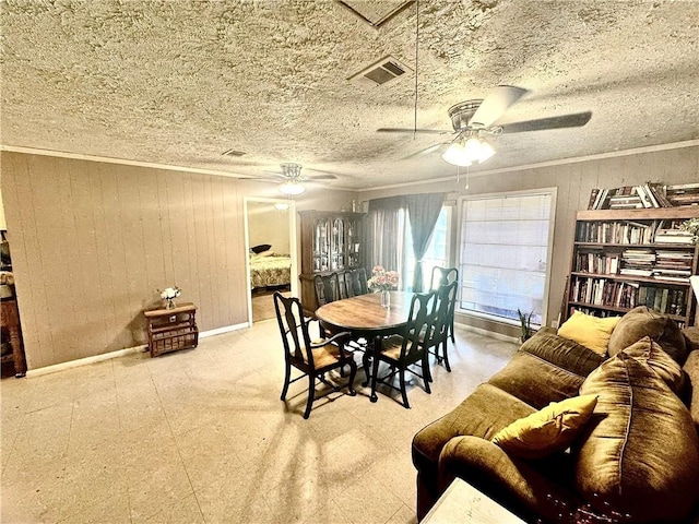 dining area featuring a textured ceiling, ornamental molding, and wood walls