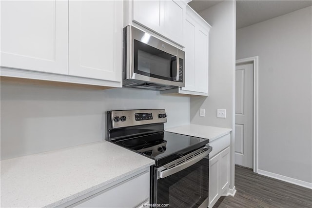 kitchen featuring stainless steel appliances, white cabinetry, dark hardwood / wood-style flooring, and light stone counters