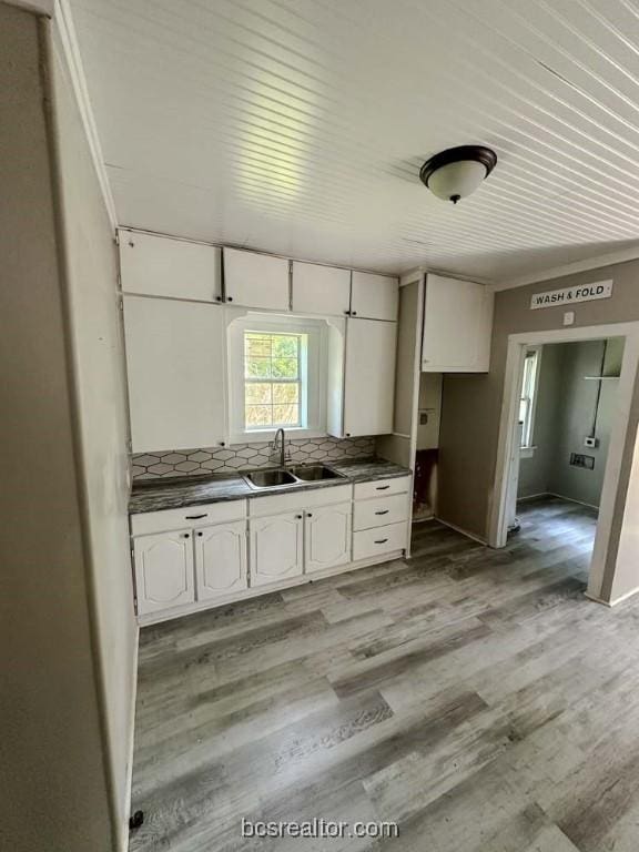 kitchen with backsplash, white cabinetry, sink, and light hardwood / wood-style floors