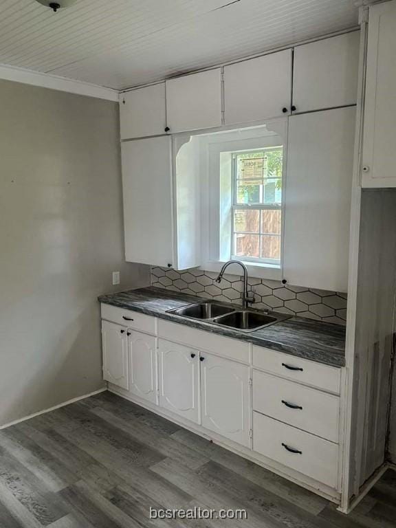 kitchen featuring wood-type flooring, white cabinetry, sink, and tasteful backsplash