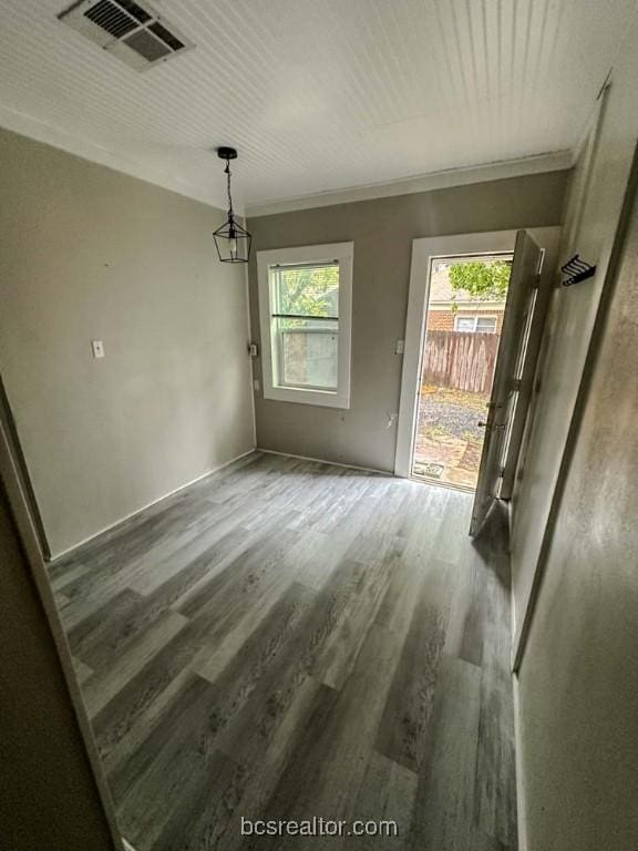 unfurnished dining area featuring plenty of natural light, wood-type flooring, and crown molding